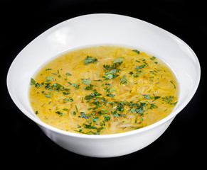 Vegetable soup, broth with noodles, herbs, parsley and vegetables in bowl, isolated on black background, healthy food. Top view.