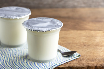 A breakfast of yogurt with a spoon placed on a wooden table.