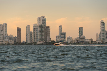 Fototapeta na wymiar Fast boat at sunset on the coast of Cartagena with modern buildings in the background. Colombia