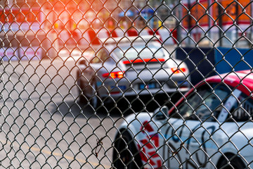 Motorsport car racing on asphalt road. View from the fence mesh netting on blurred car on racetrack...