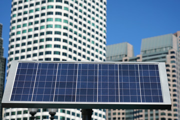 Fototapeta premium solar panel in front of downtown skyscrapers
