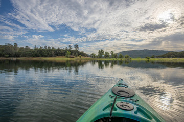 Early morning kayak excursion in scenic lake with cloud and sky reflection in water