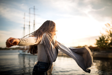 girl dancing next to the waterfront at sunset