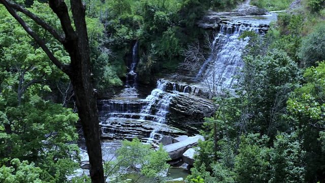 Panoramic aerial view of spectacular deep forest waterfall. Water flowing over cascading rocks into the forest floor. Aerial jungle landscape view. 