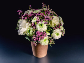 Bouquet of flowers in a coffee cup on a dark blue background. Flower compliment