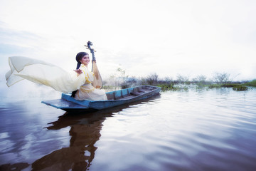 Chinese girl is playing the traditional Chinese musical instrument on the boats in the  lake...