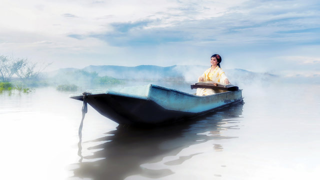 Chinese girl is playing the traditional Chinese musical instrument on the boats in the  lake ;Chinese plucked zither a traditional chinese musical