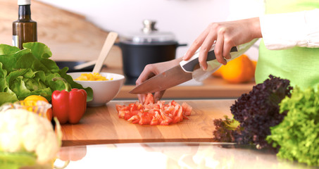 Close Up of human hands cooking vegetable salad in kitchen on the glass table with reflection. Healthy meal, and vegetarian food concept