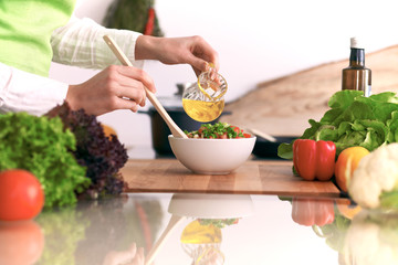 Close Up of human hands cooking vegetable salad in kitchen on the glass table with reflection. Healthy meal, and vegetarian food concept