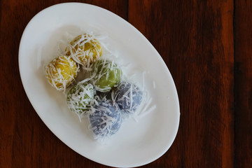 Thai coconut muchkins on white ceramic plate on wood table,  Thai tradition sweet