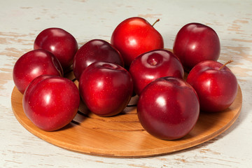 Ripe red plums on a wooden stand