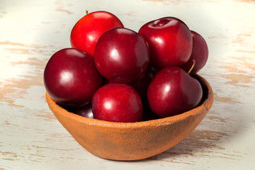 Ripe red plums in a clay plate