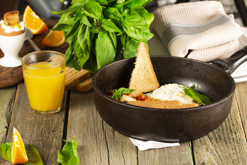English Breakfast in cooking pan with fried eggs, sausages, bacon, beans, toasts and coffee on dark stone background