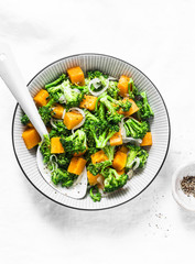 Broccoli, pumpkin warm salad  on a light background, top view. Copy space
