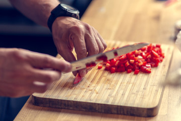 Chopping vegetables on a wooden board at home. Shallow depth of field.