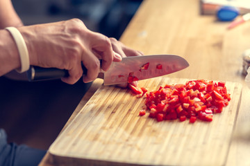 Chopping vegetables on a wooden board at home. Shallow depth of field.