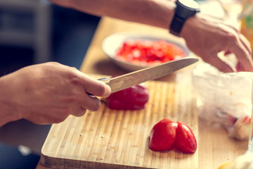 Chopping vegetables on a wooden board at home. Shallow depth of field.