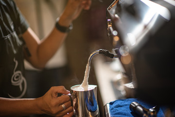equipment, coffee shop, people and technology concept - close up of woman making coffee by machine at cafe bar or restaurant kitchen