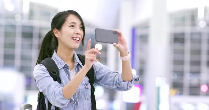 Woman taking photo on cellphone in airport