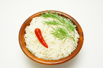 White rice with hot pepper and a sprig of dill in wooden bowl.