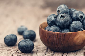Blueberries in a wood bowl on a wooden table, Healthy eating and nutrition concept