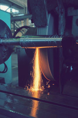 Grinding the shaft on the machine with sparks and cooling, at different angles.