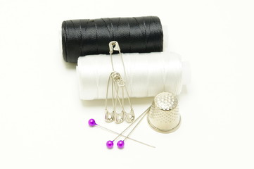 Black and white threads with pins, needles and thimble.