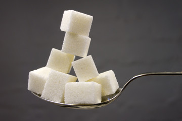 White sugar cube on a golden boat and on a colored background.