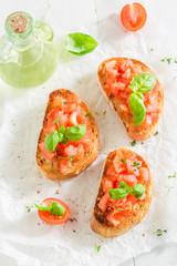 Delicious bruschetta with basil and tomato on white table