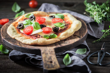 Ready to eat pizza with tomatoes, basil and olives