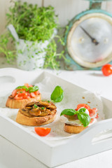 Various bruschetta with fresh ingredients on white table