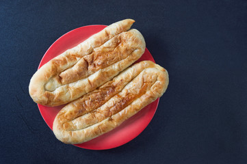 Balkan cuisine. Two bureks on red plate. Burek is popular national dish, it is hot cake made with...