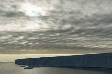 A beautiful silhouette of a very large iceberg in the Arctic under a cloudy sky