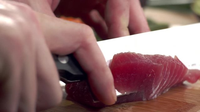 Close-up shot of sharp japenese knife slicing fresh tuna