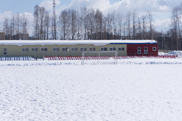 Football field in snow in the winter. A white marking on a green field and white gate for game in football.