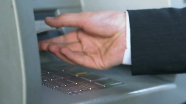 Male hands entering pin code on ATM and receiving Japanese yen, banking service