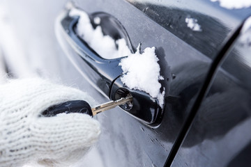 Young beautiful lady in pretty white knitted mittens try to open vehicle on a winter morning. Close-up of a key inserted into the lock of frozen car door. Transportation and ownership concept. - 214324791