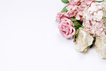 Frame made of pink and beige roses, green leaves, blue hydrangea, branches on white background. Flat lay, top view. Wedding's background. Valentine's background with copy space.