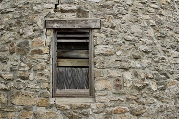 Fototapeta na wymiar Wood plank window on a very old round stone tower grist mill (windmill)