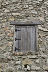 Fototapeta na wymiar Wood plank window on a very old round stone tower grist mill (windmill)