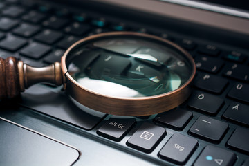 Vintage Magnifying Glass On A Black Notebook Keyboard - SEO Concept