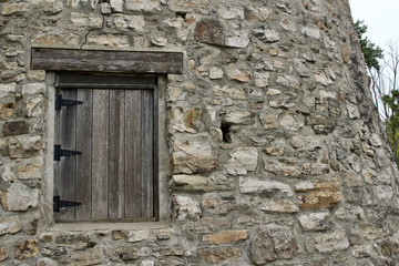 Wood plank window on a very old round stone tower grist mill (windmill)