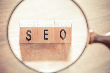 Looking Through A Magnifying Glass On SEO Blocks - Search Engine Optimization Concept