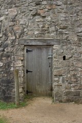 Fototapeta na wymiar Wood plank entrance door to a very old round stone tower grist mill (windmill)