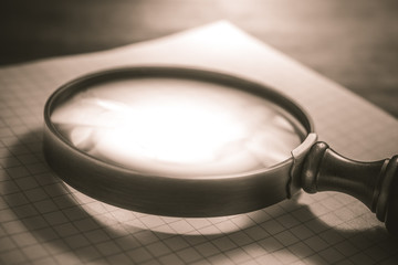 Vintage Loupe Lying On An Open Checkered Diary In Sepia Colors