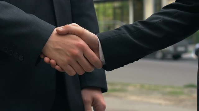 Handshake of two businesspeople standing near office, agreement, partnership