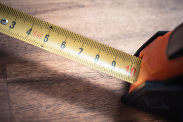 Macro Of A Solid Measuring Tape With Pulled Out Scale Standing On A Table