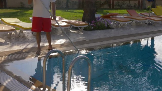 Hotel worker cleaning water in swimming pool, cropped view