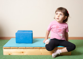 little girl, 3 years old. doing yoga with cubes