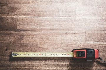 Solid Measuring Tape With Pulled Out Scale Lying At The Bottom Of A Wooden Table, Top Down View